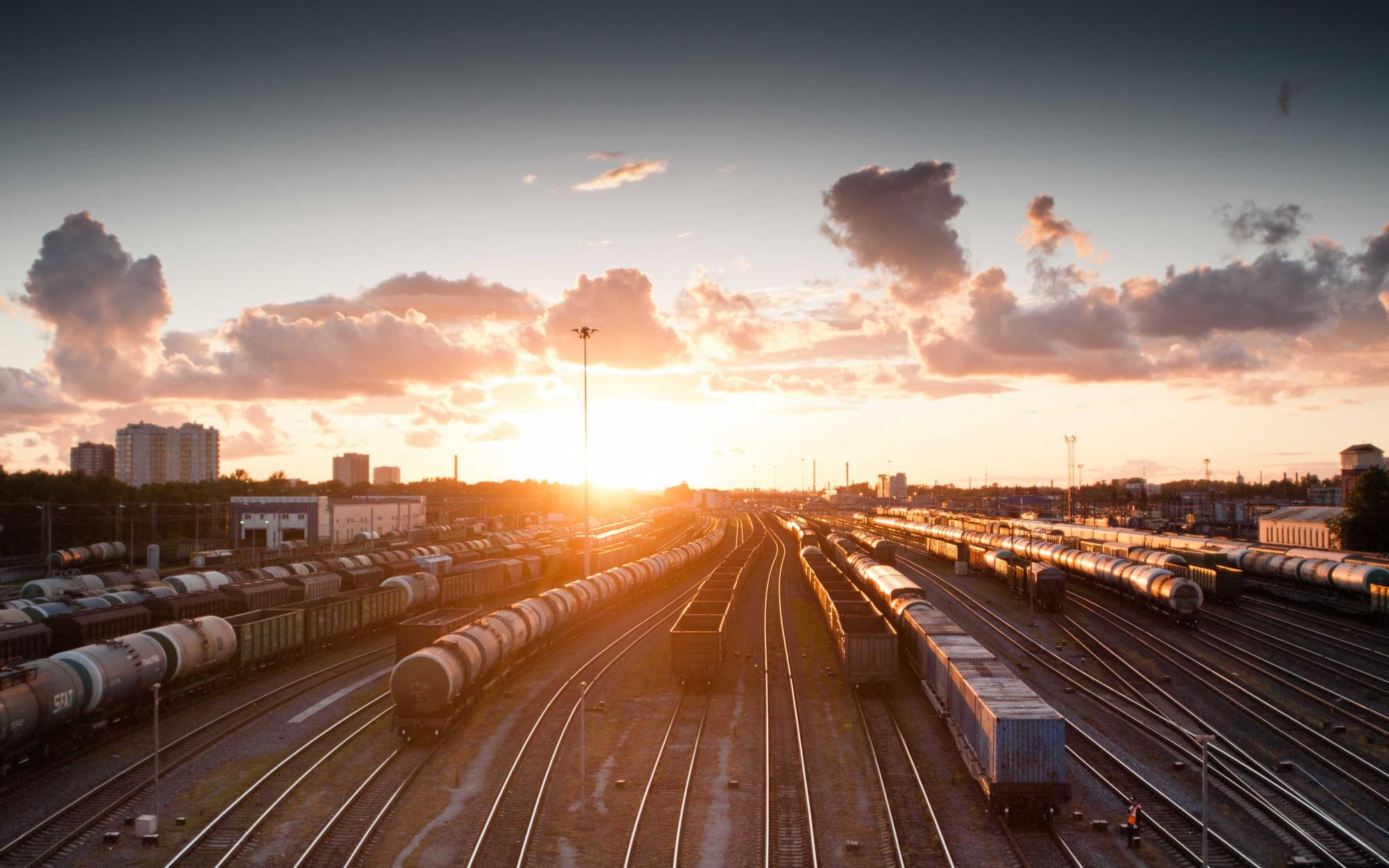 Rail yard at dusk, parallel tracks converging toward the horizon